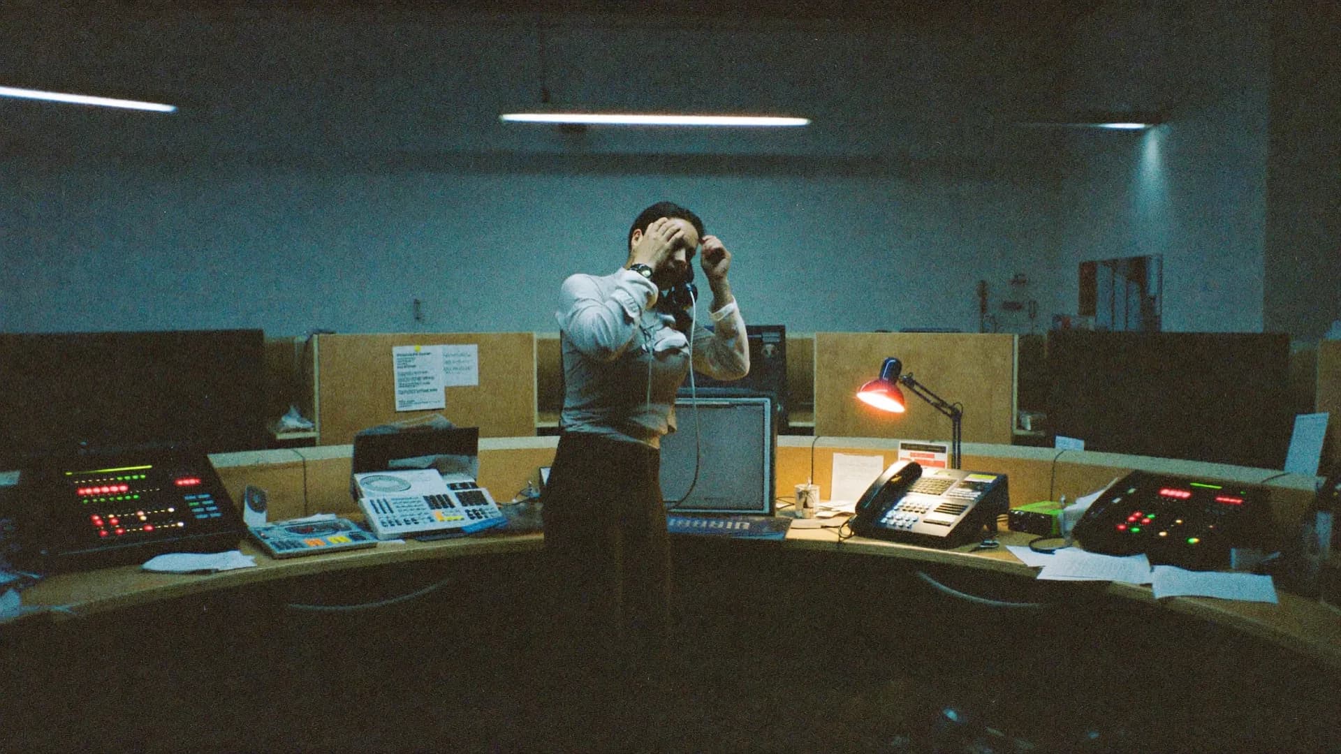 A dispatch desk at night: a red lamp, a desk phone and a console of status lights